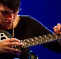 Kaki King taps the neck of her guitar.